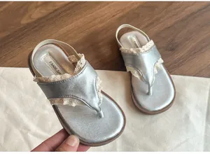 Gros plan de sandales argentées pour enfants avec dentelle délicate et semelle souple
