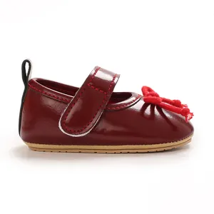 Nahaufnahme weinroter Lackleder-Babyschuhe Mary Jane mit charmanter roter Schleife.