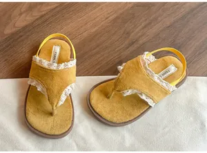 Détail du daim jaune et de la dentelle blanche sur les sandales à semelle souple enfant