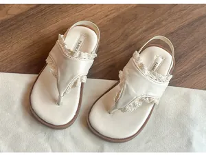 Vue détaillée d'élégantes sandales à entre-doigt crème pour enfants avec dentelle délicate