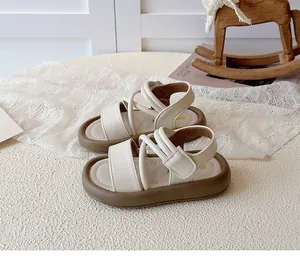 Close-up of off-white children's Roman sandals showing strap details and thick brown soft soles.