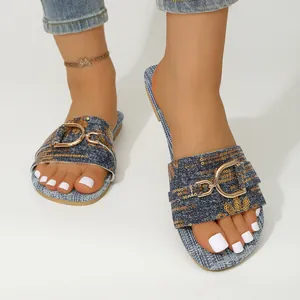 Detail view of denim slides featuring gold sequins and metal buckle, square toe.
