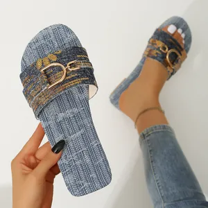 Detail view of stylish denim slide sandals with gold buckle and square toe for women.