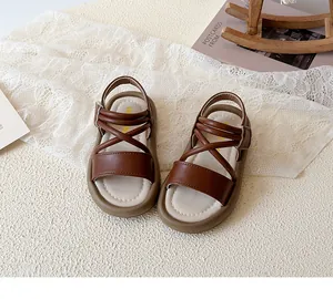 Close-up of brown children's Roman sandals featuring cross straps and a soft, anti-slip sole