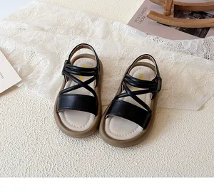 Close-up detail of black crisscross strap sandals for girls with soft brown sole