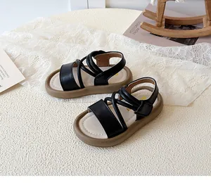 High-angle detailed shot of children's black Roman sandals featuring soft brown soles