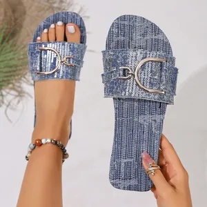 Close-up of blue denim flat sandals featuring sequins and a gold horsebit buckle