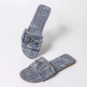 Detail of stylish denim flat sandals featuring a signature gold D-buckle and square toe