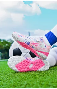 Detailed macro shot of pink and purple children's TF turf soccer shoes on field