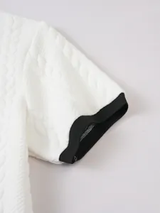Close-up of men's white jacquard polo shirt with black contrast ribbed cuffs