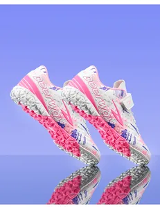 Detailed view of pink and purple turf soccer shoes for kids training on artificial grass