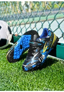 Detail of professional TF soccer cleats with blue splash pattern and durable rubber sole