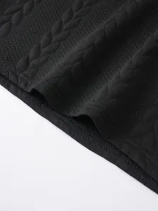 Close-up of black jacquard knit fabric showing cable pattern and seam detail
