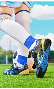 Detail shot of kids soccer shoes with blue and yellow patterns on artificial turf
