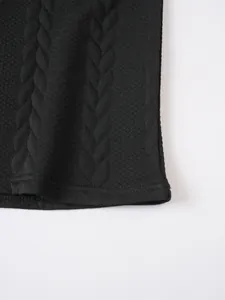 Detailed close-up showing the intricate black jacquard knit texture and hemline of a men's polo shirt.
