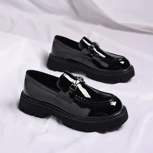 Shiny black patent leather loafers with thick lug soles and metal buckle details.