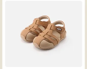 Nahaufnahme brauner Kleinkindersandalen mit weicher Sohle, Lochmuster und Klettverschluss.