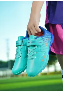 Detail view of kids' turquoise turf soccer shoes featuring a secure velcro strap closure.