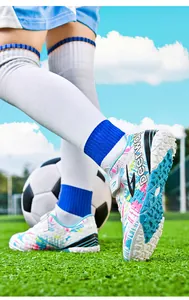 Close-up of children's soccer shoes with colorful patterns on a turf field