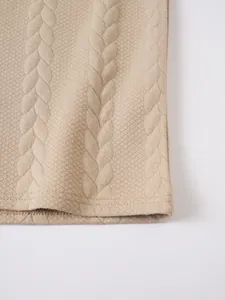 Close-up view of the jacquard textured fabric and hem of a beige men's polo shirt