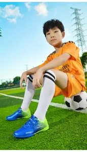Blue and green children's turf soccer cleats with velcro strap on artificial grass.