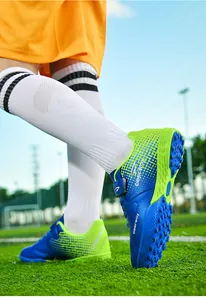 Detailed view of kids' blue and lime green turf soccer cleats with Velcro straps
