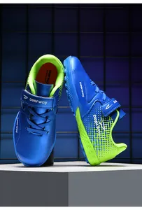 Close-up of vibrant blue and green kids' soccer cleats with deerway logo and velcro strap.