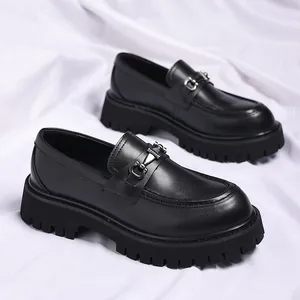 Detailed view of black platform loafers with metal link buckle on white cloth