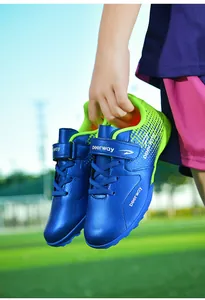 Close-up of blue children's TF soccer shoes with green details and velcro straps
