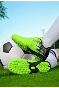 Close-up of professional children's lime green TF soccer shoes with turf studs on grass