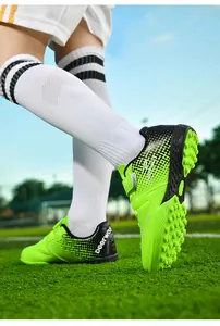 Detail view of kids neon green TF turf soccer shoes with velcro strap on field