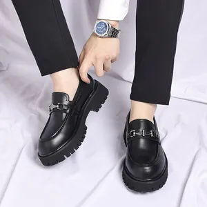 Stylish men's black chunky loafers with metallic buckle detail worn on white backdrop