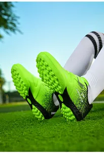 Macro view of bright neon green kids' turf soccer shoes showing rubber stud outsoles