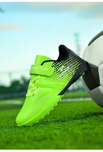 Close-up of bright green children's soccer cleats on turf with soccer ball