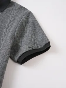 Close-up of grey textured jacquard polo shirt with black ribbed sleeve detail