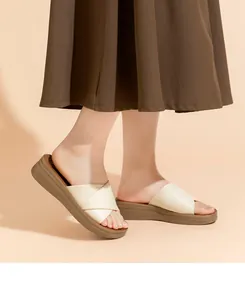 Seitenansicht beiger Keilsandalen mit Kreuzriemen, getragen zu einem braunen Rock.