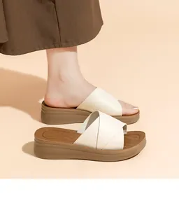 Nahaufnahme von Damen-Keilsandalen in Creme mit brauner Plateausohle und Kreuzgurten