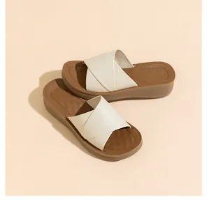 Detailansicht der cremefarbenen Kreuzriemen und der braunen Plattform-Sommerschuhe