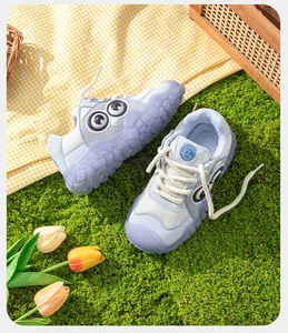Gros plan de baskets bleues pour enfants avec un joli design d'yeux sur herbe artificielle