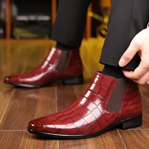 Dettaglio degli stivaletti Chelsea da uomo bordeaux con motivo coccodrillo su pavimento in legno
