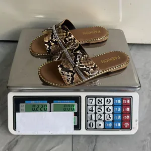 Misurazione del peso dei sandali piatti con motivo a serpente e decorazione di strass