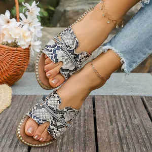 Primo piano di sandali bassi alla moda con motivo a serpente e cinturini in strass lucenti