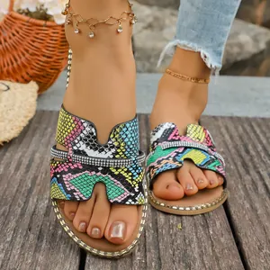 Primo piano di sandali colorati da donna con stampa serpente e dettagli in strass lucidi