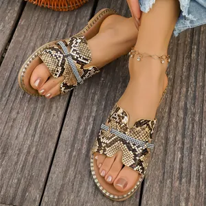 Dettaglio di ciabatte basse da donna con elegante motivo a serpente e strass brillanti