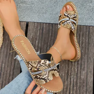 Dettaglio di sandali bassi da donna con stampa pitonata e cinturini decorati in strass