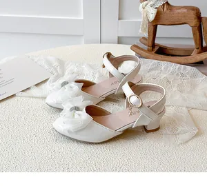 Detailed view of girls' white high-heeled sandals featuring rhinestone mesh bow and strap