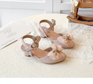 Detail of children's pink high-heeled sandals with elegant rhinestone bow and ankle strap