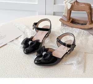 Detailed view of black girls high-heel sandals with elegant rhinestone bow decoration