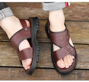 Nahaufnahme der braunen Herren-Ledersandalen mit Kroko-Struktur auf Holzhintergrund