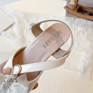Elegant white girls' high-heeled sandals featuring a rhinestone bow and pointed toe